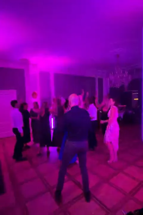 Bryllupsgæster på dansegulvet i magenta lys